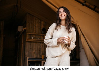 Positive young caucasian girl smiling looks away relaxing in campsite on weekend. Brunette wears white sweatshirt and shorts. People emotions, lifestyle concept - Powered by Shutterstock