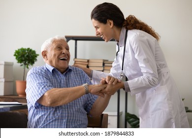 Positive young female nurse have fun laugh and joke with happy elderly male patient at consultation in hospital. Caring woman doctor support cheer and comfort mature man. Good medicine concept.