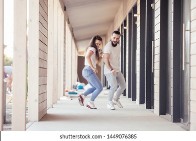 Positive young happy couple newlyweds dance synchronously walking around their hotel room in a tropical country during their holidays. Travel enjoyment concept