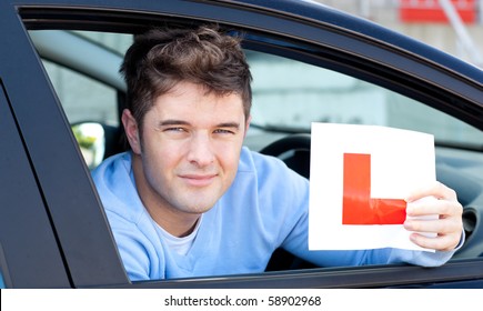 Positive young male driver holding a L sign sitting in his car