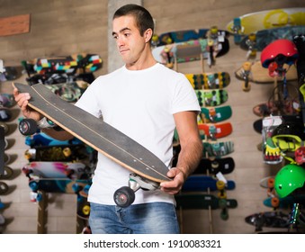 Positive young man choosing skateboard in store - Powered by Shutterstock