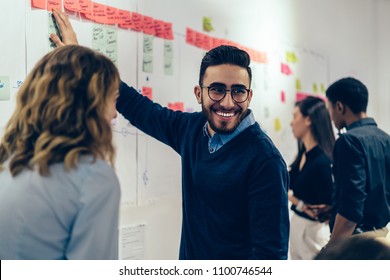 Positive young man laughing while collaborating with colleagues on creating presentation using colorful stickers for productive work in office.Male and female students having fun during workshop - Shutterstock ID 1100746544
