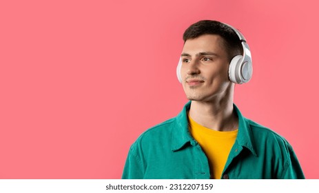 Positive young man listening music, enjoying dance with headphones on pink studio background. Radio, wireless modern sound technology, online player. Copy space. High quality - Powered by Shutterstock