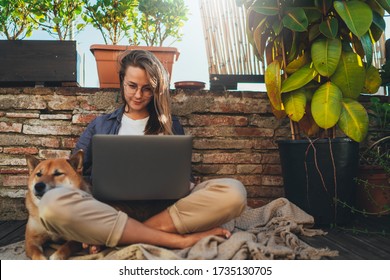 Positive Young Millennial Girl With Long Hair Sitting Outdoor At Home Terrace With Best Friend Dog Working On Distance Using Laptop, Beautiful Student Girl Having Online Video Meeting Via Computer