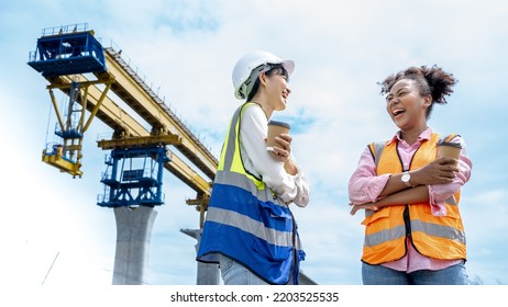 Positive Young Multi Ethnic Diversity Female Construction Workers Drinking Coffee From Disposable Cups And Talking While Resting During Break.Civil Engineer Bridge Project .Project Manager Smiling.