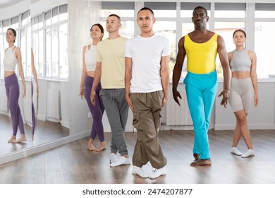 Positive young multinational people forming line while rehearsing traditional Irish stepdance in modern dance studio - Powered by Shutterstock