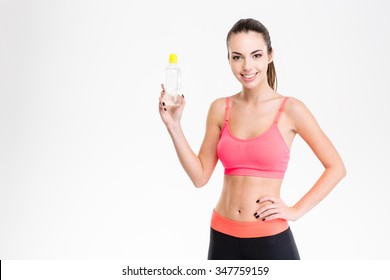 Positive young sportswoman holding a bottle of water isolated over white background