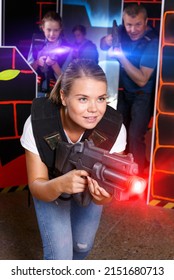 Positive Young Woman Holding Laser Gun And Playing Lasertag Game With Family In Arena.