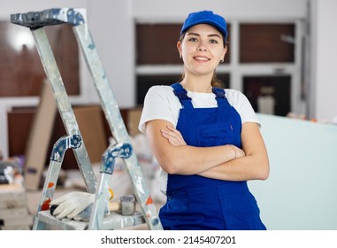 Positive young woman repairer in uniform standing inside apartment and looking at camera. - Powered by Shutterstock