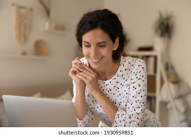 Positive Young Woman Stand By Desk With Laptop Look On Screen With Smile Read Good News At Internet Watch Cute Video. Pleasant Lady Housewife Take Break From Routine Chores To Spend Free Minute Online