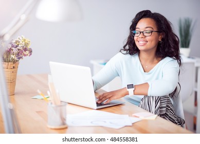 Positive young woman using laptop
