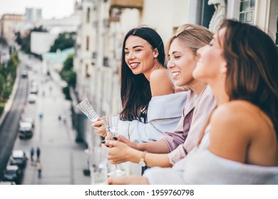 Positive Young Women Group In Stylish Pajamas With Delicious Champagne Bottles Dances On Open Hotel Room Balcony At Happy Bachelorette Party