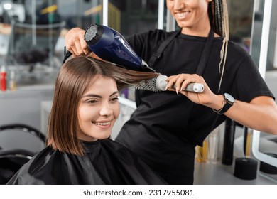 positivity, salon blow dry, professional hairdresser with round brush and hair dryer styling hair of female customer, happy brunette woman with short hair, beauty salon, hair volume, blowout - Powered by Shutterstock