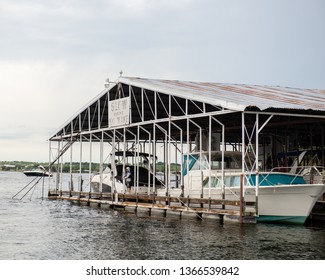 Possum Kingdom Lake, Texas / USA June 21 2017 A Young Boy Wearing A Hoodie And Life Jacket Fishes Off Of A Dock In The Marina With A No Wake Sign Overhead And A Boat In The Background