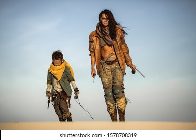 Post apocalyptic woman and boy heroically walking with weapons outdoors. Gray sky and dead wasteland on the background. Attractive fighter girl warrior in shabby clothes with knife and monocle
