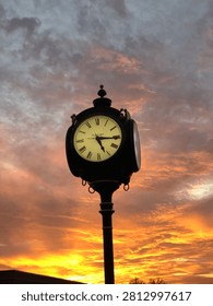 Post clock with sunset on a cloudy day