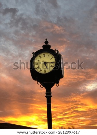 Post clock with sunset on a cloudy day