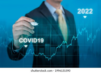 Post Covid-19 Economic Recovery In 2022 Concept. Businessman Hand With Marker Pointing Graph Growth Plan On Blue Background. Timeline Chart Diagram Of Global Economic After Crisis By Covid19 Pandemic