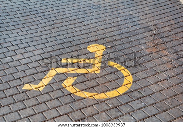 Post with disabled parking space and sign in\
front of parking bay in car park / Marked parking for people with\
special needs / Handicapped symbol, sign on asphalt, painted detail\
of road and street.
