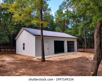 Post frame garage with metal siding, metal roof, two roll-up doors, one entry door, windows, concrete floor - Shutterstock ID 1997149154