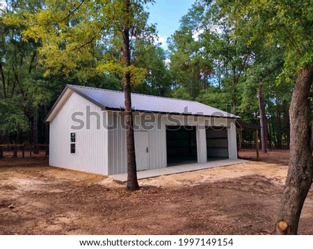 Post frame garage with metal siding, metal roof, two roll-up doors, one entry door, windows, concrete floor