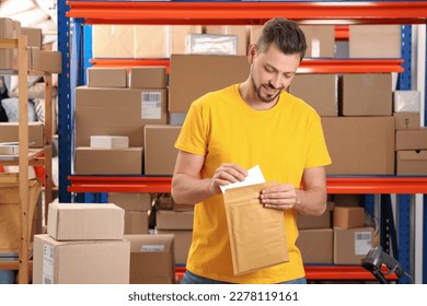Post office worker putting envelope into adhesive bag indoors