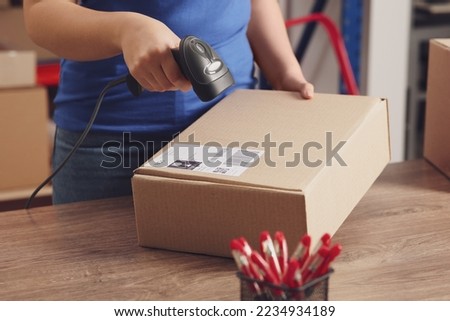 Post office worker with scanner reading parcel barcode at counter, closeup
