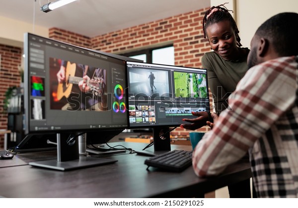 Post production department leader advising\
colleague to improve colors and frames quality of footage. Creative\
professional video editors collaborating in order to finish film\
project upon deadline.
