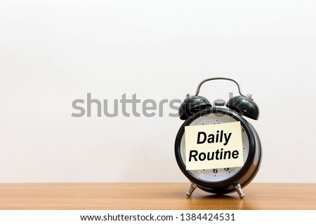 Post it word daily routine alarm clock on wood desk white background. 
Sticker notepad paper message daily routine and watch on wooden table for copy space. 