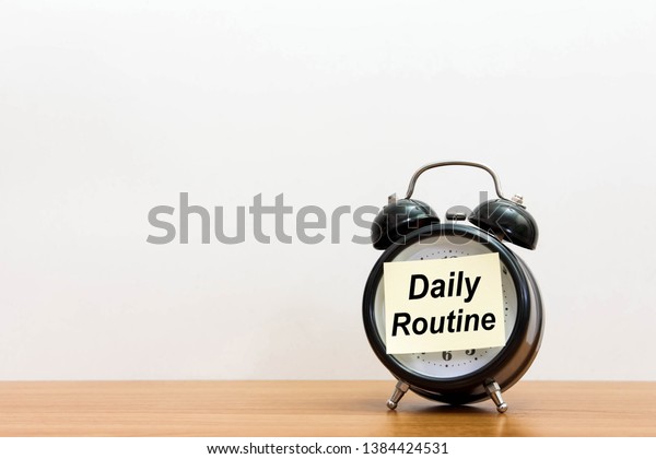 Post it word daily routine alarm
clock on wood desk white background. 
Sticker notepad paper
message daily routine and watch on wooden table for copy space.
