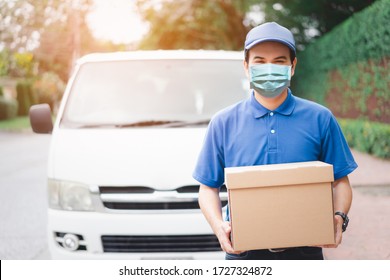 Postal delivery courier man wearing protective face mask in front of cargo van delivering package holding box due to Coronavirus disease or COVID-19 outbreak situation in all of landmass in the world.