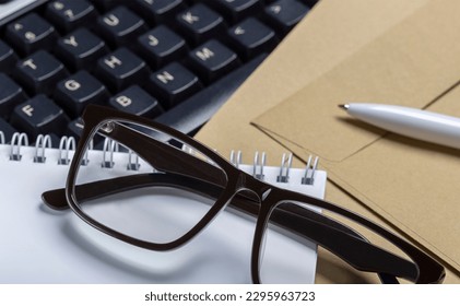 postal envelopes, computer keyboard, glasses and ballpoint pen