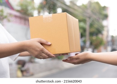 Postal service sending paper cardboard box to customer in front of a house outdoor. Shipping service arrival and send to customer address. 