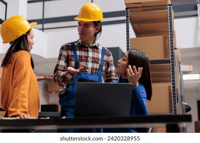 Postal service workers arguing about delivery checklist while analyzing data on laptop in warehouse. Asian man and women storehouse employees team discussing goods logistics - Powered by Shutterstock