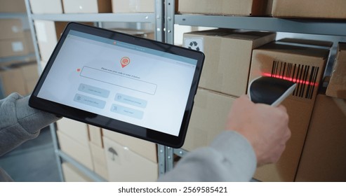 Postal Warehouse Associate Scans QR Code on Cardboard Box with Barcode Scanner, Checks Parcel Information. Tablet Computer Screen Shows Delivery Tracking App to Monitor Package Routing. Close Up.