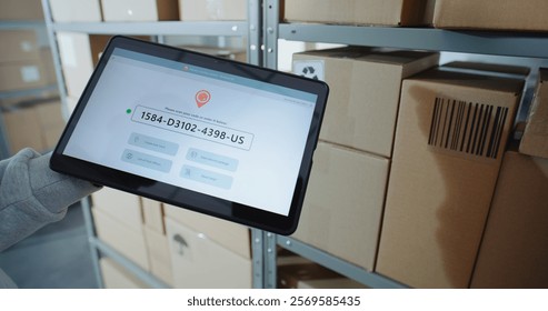 Postal Warehouse Associate Scans QR Code on Cardboard Box with Barcode Scanner, Checks Parcel Information. Tablet Computer Screen Shows Delivery Tracking App to Monitor Package Routing. Close Up.