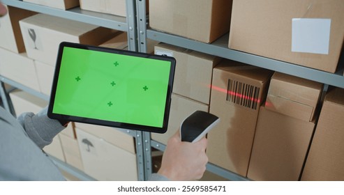 Postal Warehouse Worker Scans Code on Cardboard Box with Barcode Scanner, Checks Package Information, Monitors Parcel Delivery Route. Tablet Computer Display Shows Green Screen Chroma Key. Close Up.