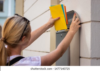 Postal Worker Is Inserting Letters Into Mailbox. Woman Is Holding Colorful Envelopes. Mail Carrier Delivering Correspondence