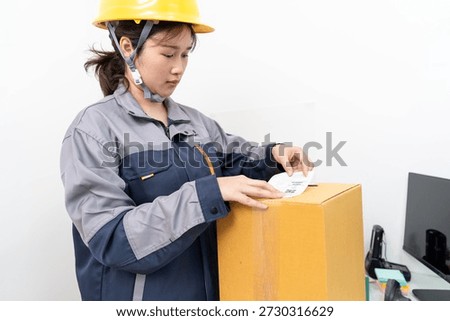 Postal workers handle parcel boxes by attaching barcode stickers.