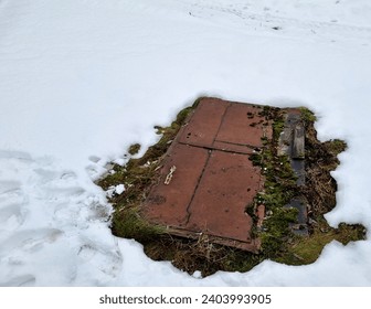 Post-apocalypse. Winter.  Old rusty iron door in the snow on the ground in winter. Entrance to the shelter, covering the traces of people entering the door