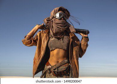 Post-apocalyptic woman with weapon outdoors. Young slim girl warrior in shabby clothes holding sword standing in a confident pose looking away. Nuclear post-apocalypse time. Life after doomsday