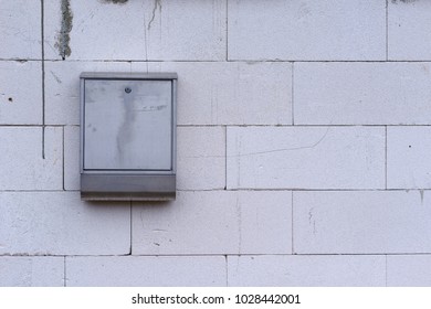 Postbox on a cement block exterior wall in a close up view
