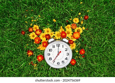 Postcard good morning and alarm clock with yellow and red flowers lie on the green grass