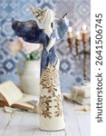 Postcard motif with blue angel figurine on the table. 