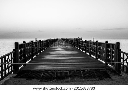 Poster design of a pier over the sea, wooden construction like a bridge, black and white photo