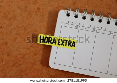 Post-it note with the words "Hora Extra" (Overtime, in Portuguese) on a personal planner. Concept of working extra hours, professional workload, and labor management. 