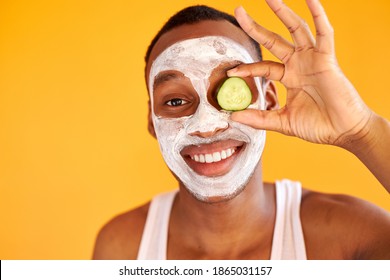 Postive Man Apply Face Mask With Cucumber Slices, Express Positive Emotions Isolated Over Yellow Background, Male Get Beauty Treatments