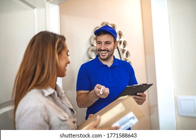 Postman Delivering Package Of Goods To Home With Smile And Happy Face. Young Cute Girl Receiving Boxes From Postman At The Door. Selective Focus On The Hands. Home Delivery Concept.