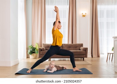 Postnatal recovery, sport for mom, happy motherhood. Healthy fit mom working out with her cute toddler baby on exercise mat at home. Smiling new mom practising yoga with her infant son, doing asana