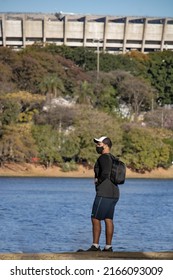 Post-pandemic tourism man standing with mask, cap and backpack on his back on the edge of Lagoa da Pampulha, near Mineirão stadium in Belo Horizonte, Minas Gerais, Brazil.
